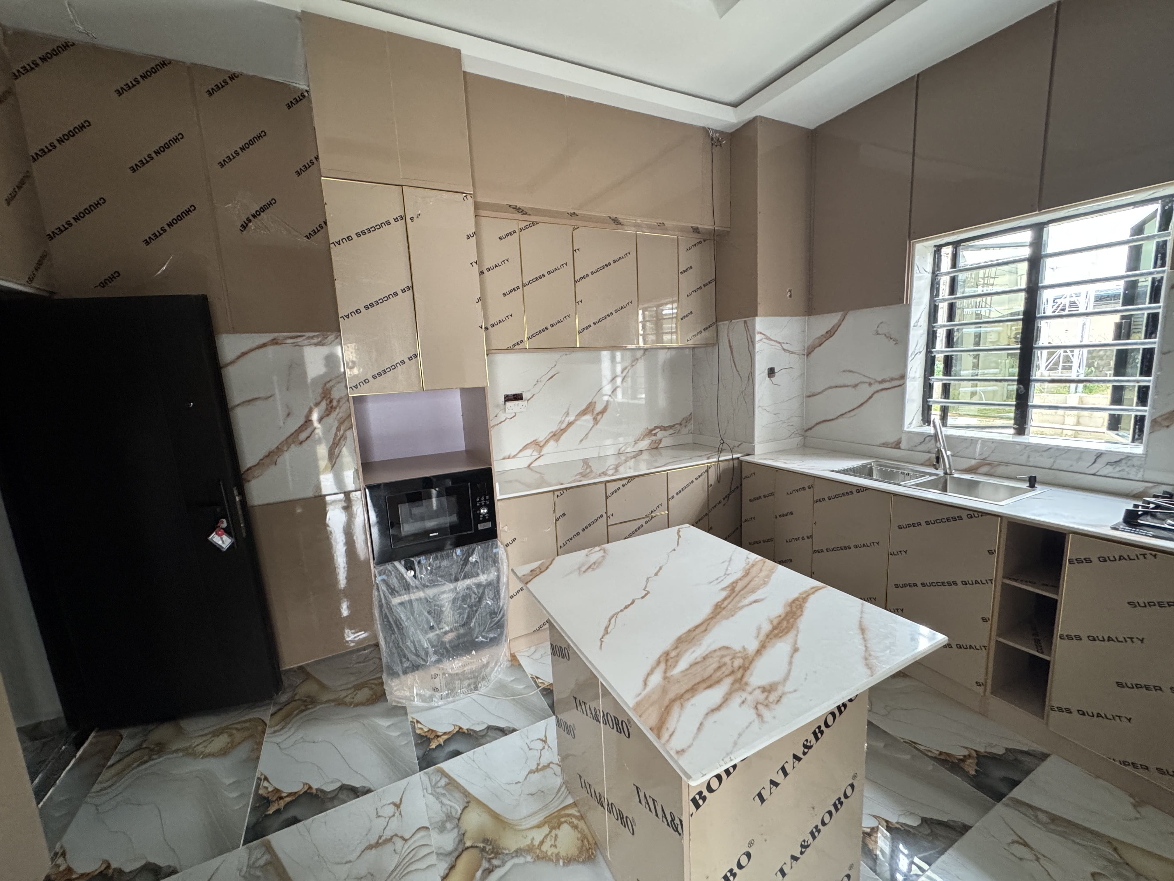 Wide angle view of a contemporary kitchen showcasing high-end protective finishes on the cabinetry and a large stainless steel double sink
